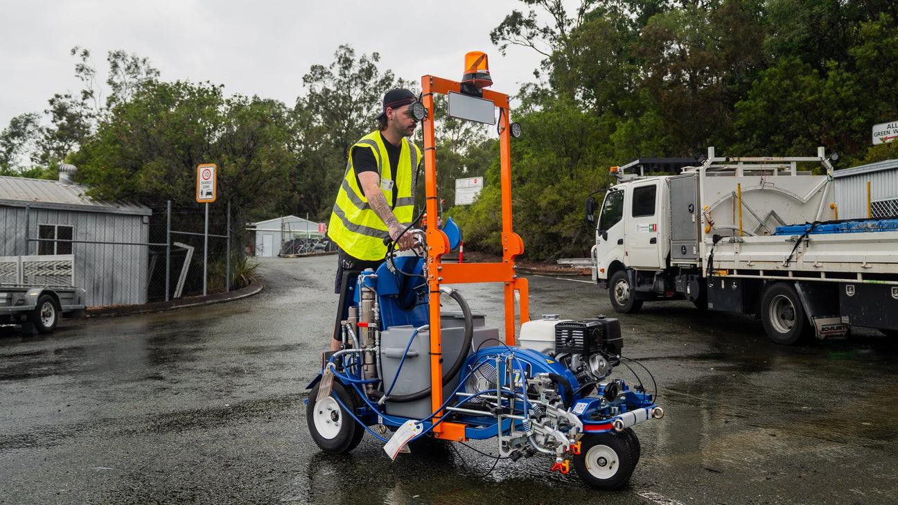 Operator pushing a Graco LineLazer fitted with the GO Industrial conditional registration kit: amber beacon, number plate, flood lights and front indicators