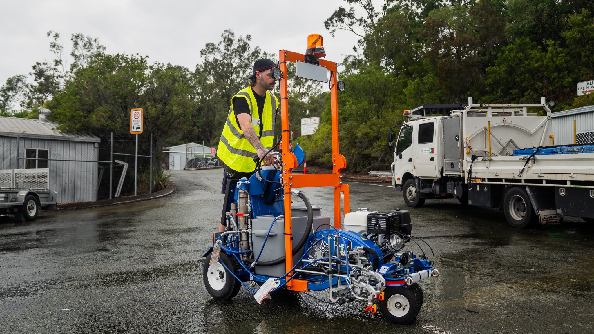 Operator pushing a Graco LineLazer fitted with the GO Industrial conditional registration kit: amber beacon, number plate, flood lights and front indicators